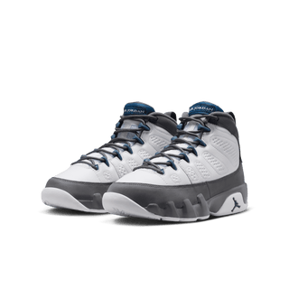 Pair of gray and white sneakers with blue accents on a dark background